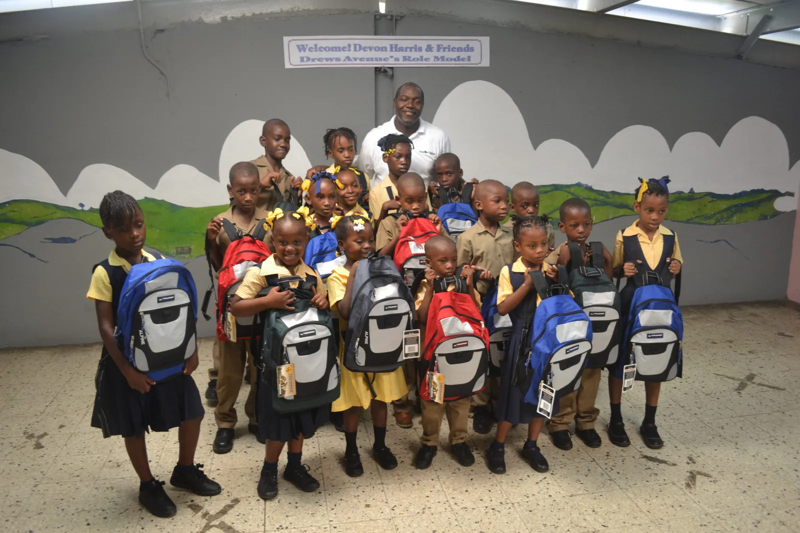 Devon Harris with Drews Avenue Primary students holding new book bags from the Keep On Pushing Foundation
