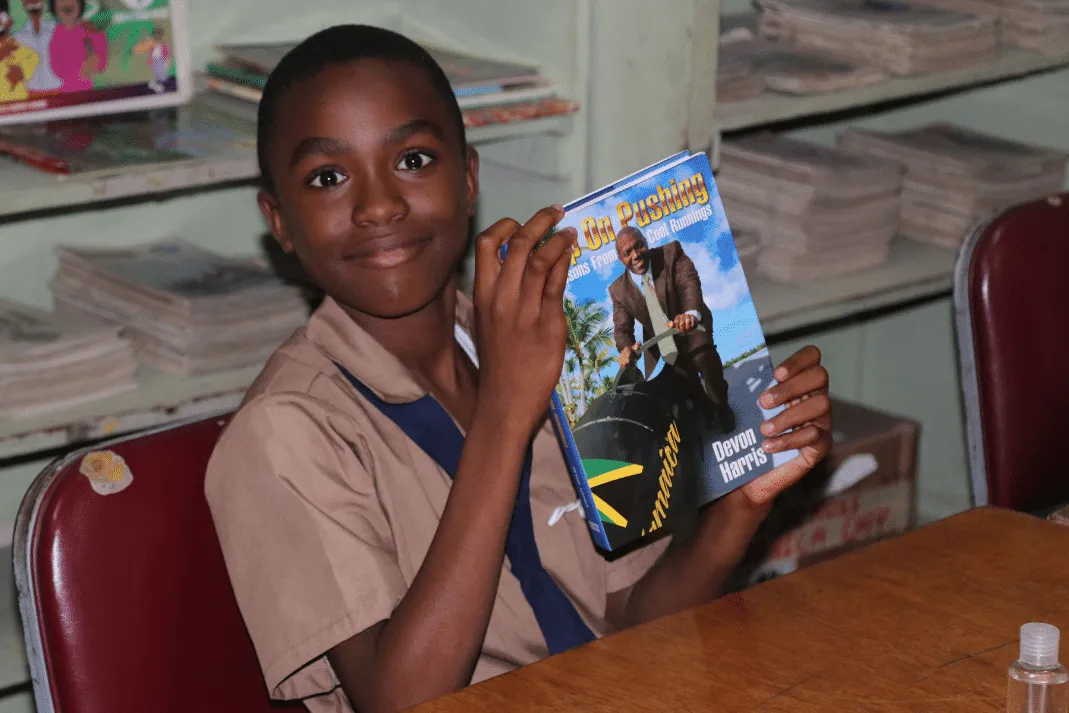 Student at Drews Avenue Primary holding a copy of Keep On Pushing by Devon Harris