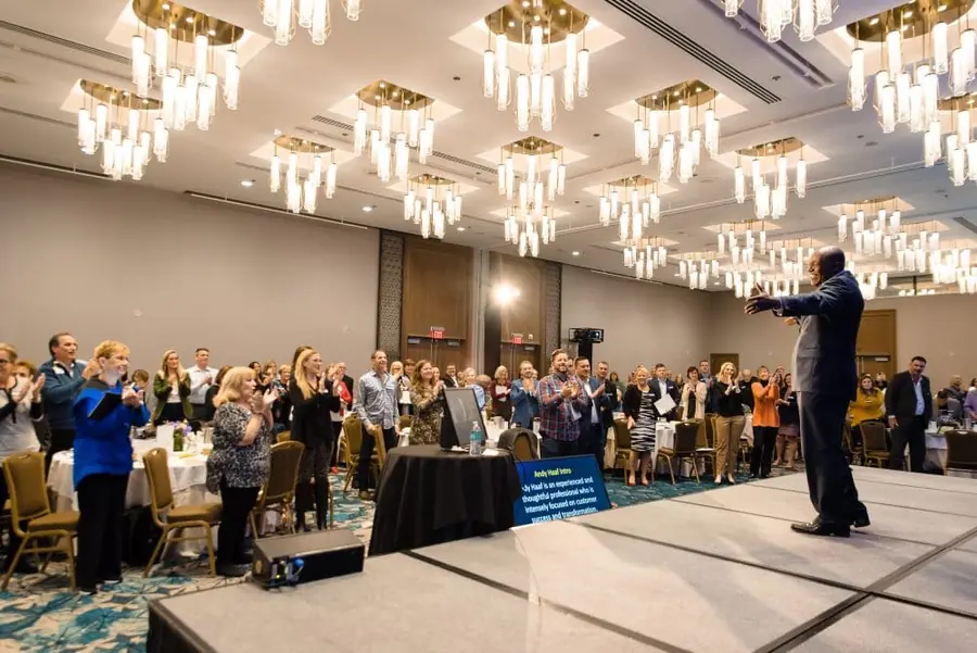 Sales team on its feet in a hotel ballroom during Devon Harris's sales kickoff keynote